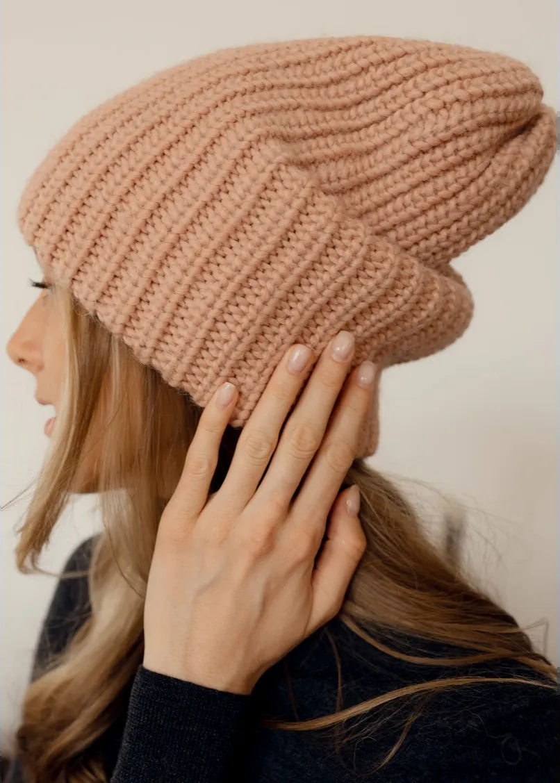 BRIKOLY London Peach knit beanie shown close up as a model touches the side.