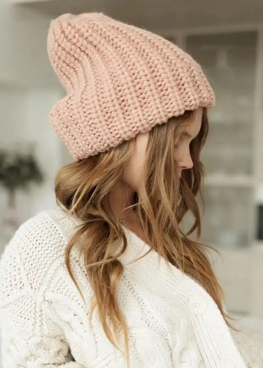 BRIKOLY London Peach knit beanie shown from the rear side on a model in a white sweater.